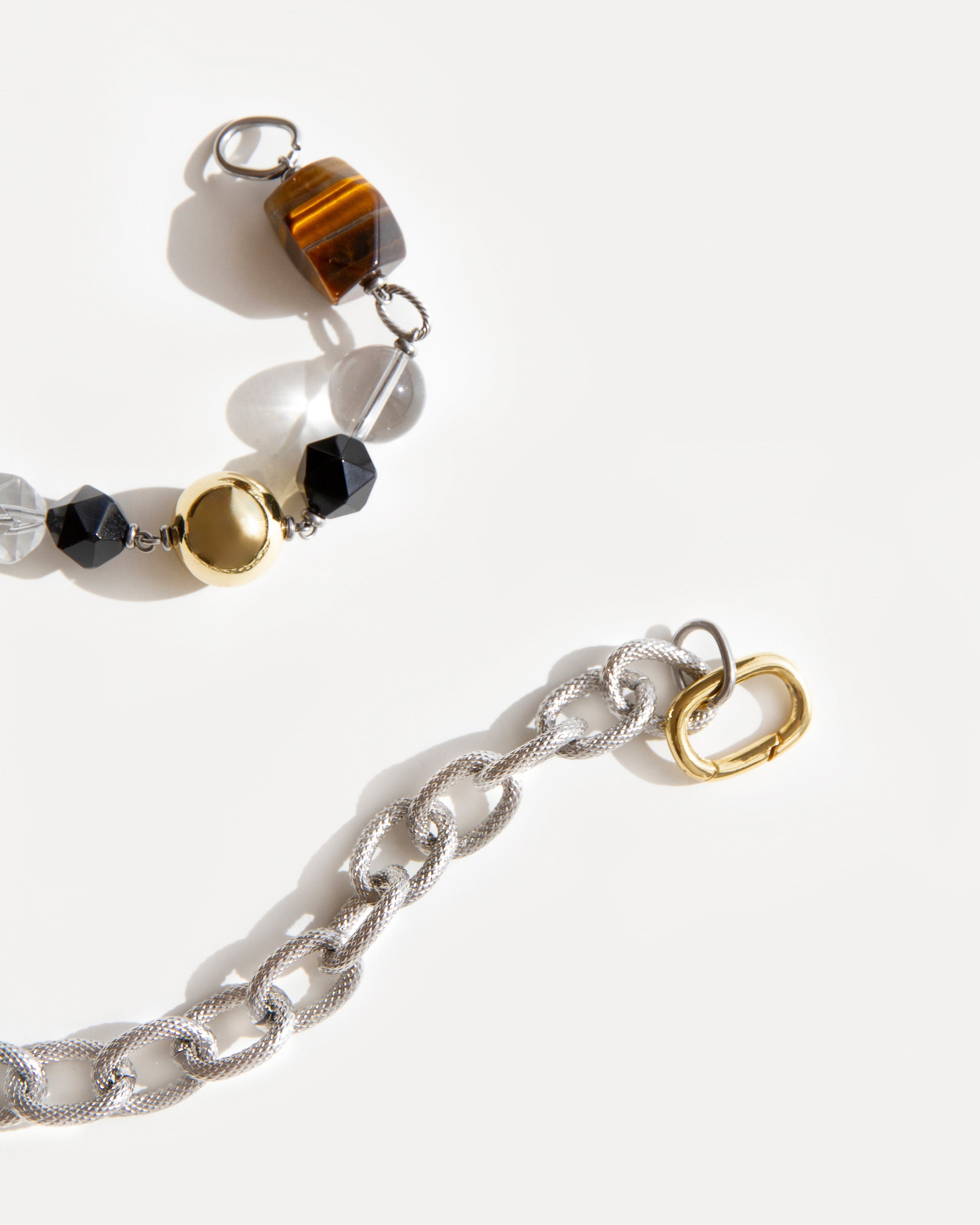 Close-up of Tiger Eye Necklace with polished tiger eye, agate, clear quartz and mixed metal chain, highlighting textures and gold-silver contrast.