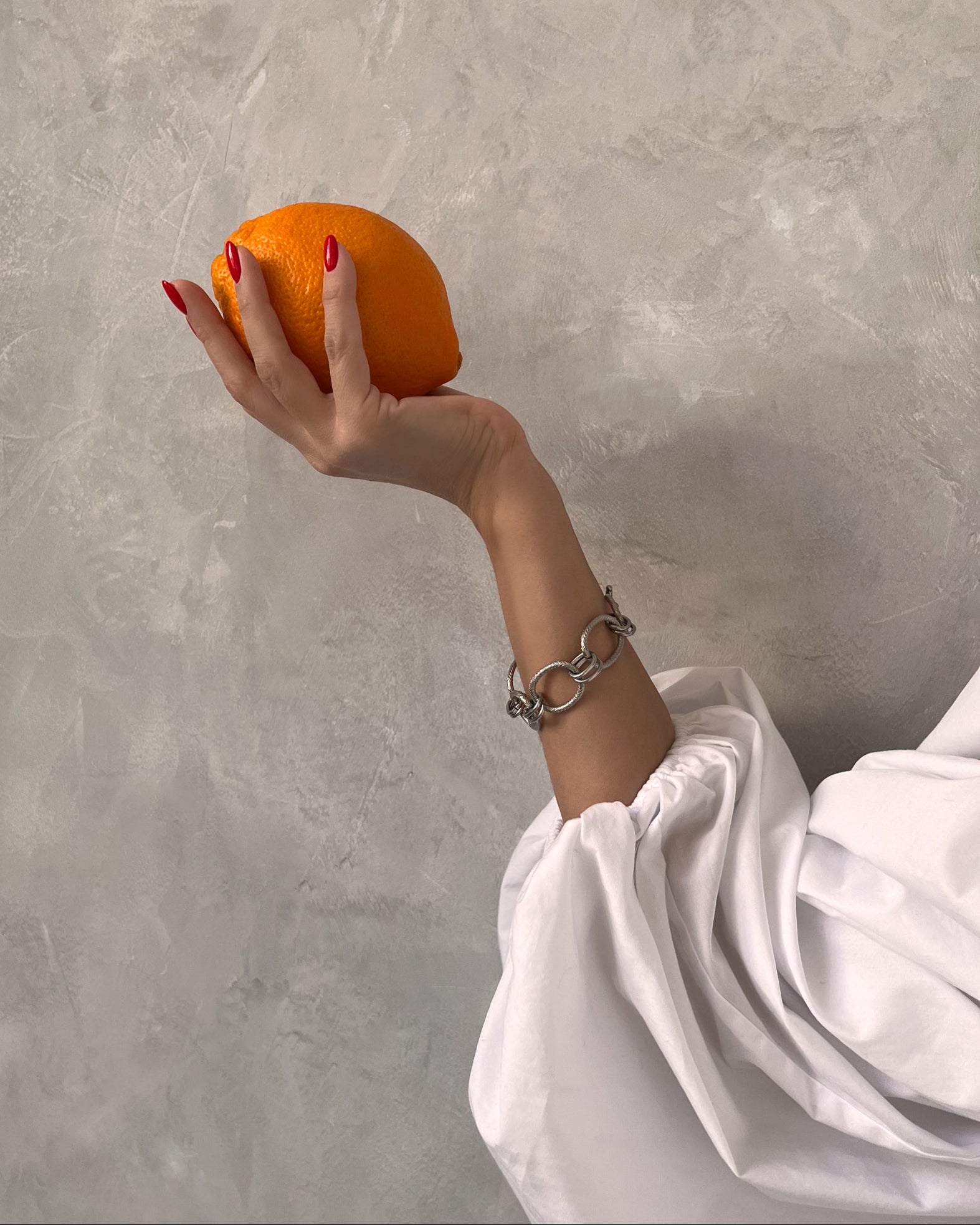 Stainless steel Venus Bracelet styled with white puff sleeve and bright orange — bold contrast and sculptural, modern elegance.