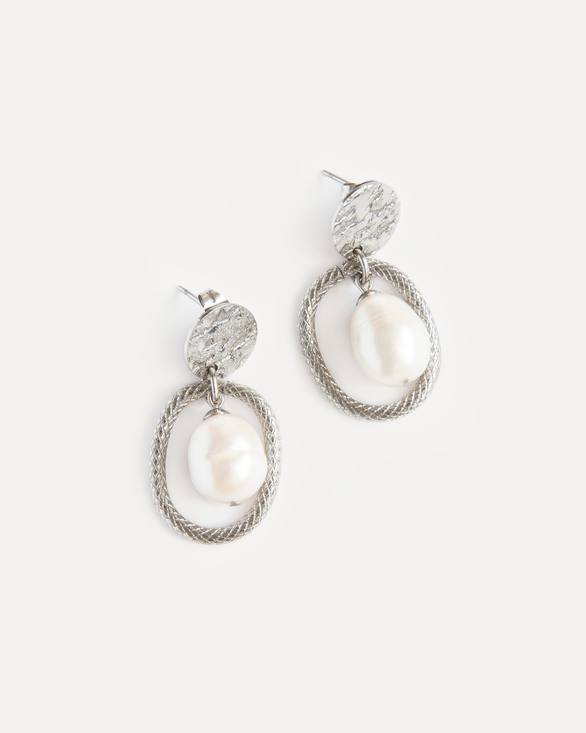 Sculptural pearl statement earrings with textured stainless steel oval frame — bold yet timeless design with modern elegance.