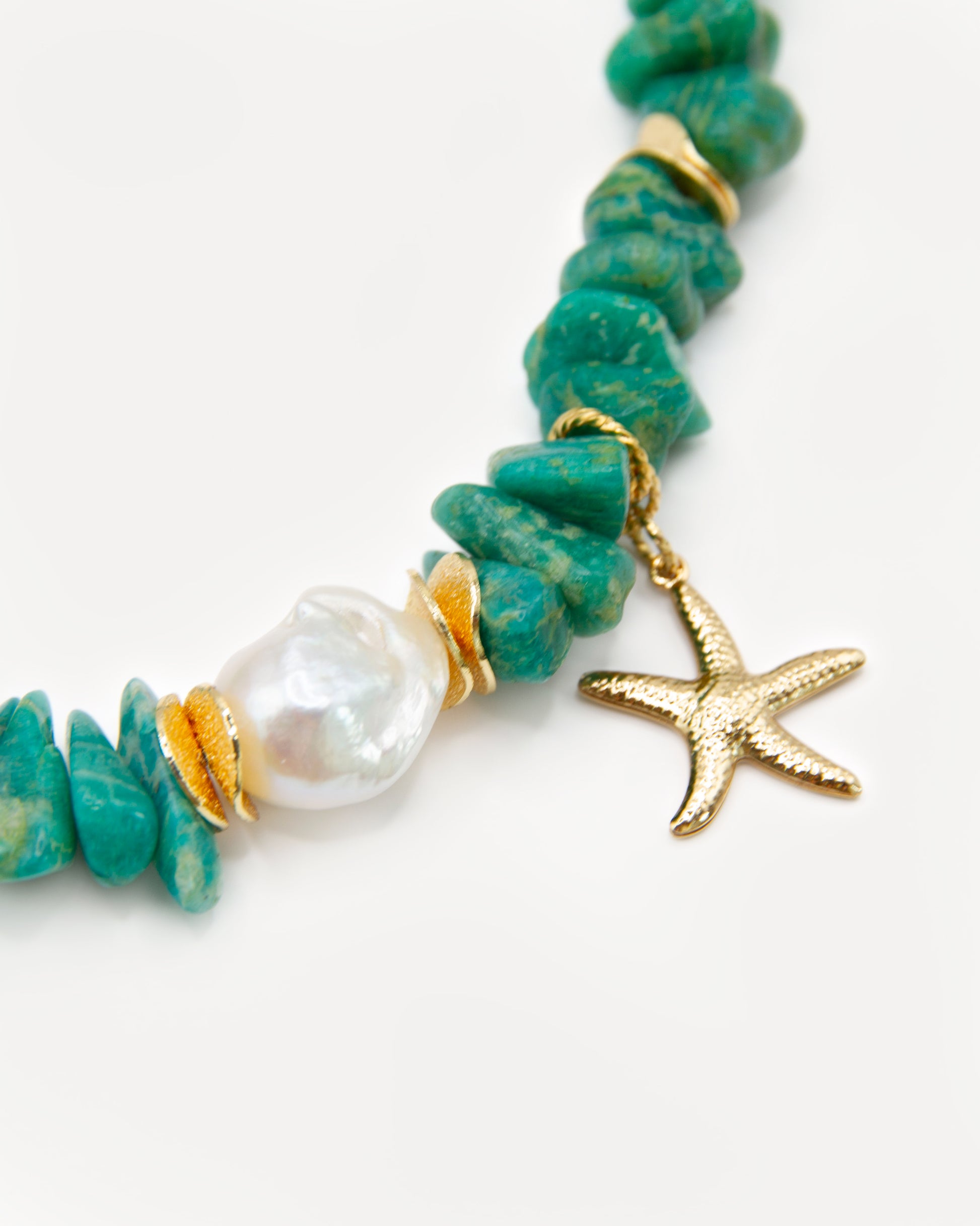 Close-up of irregular green amazonite beads, a baroque freshwater pearl and gold starfish charm on the Wild Green statement necklace.